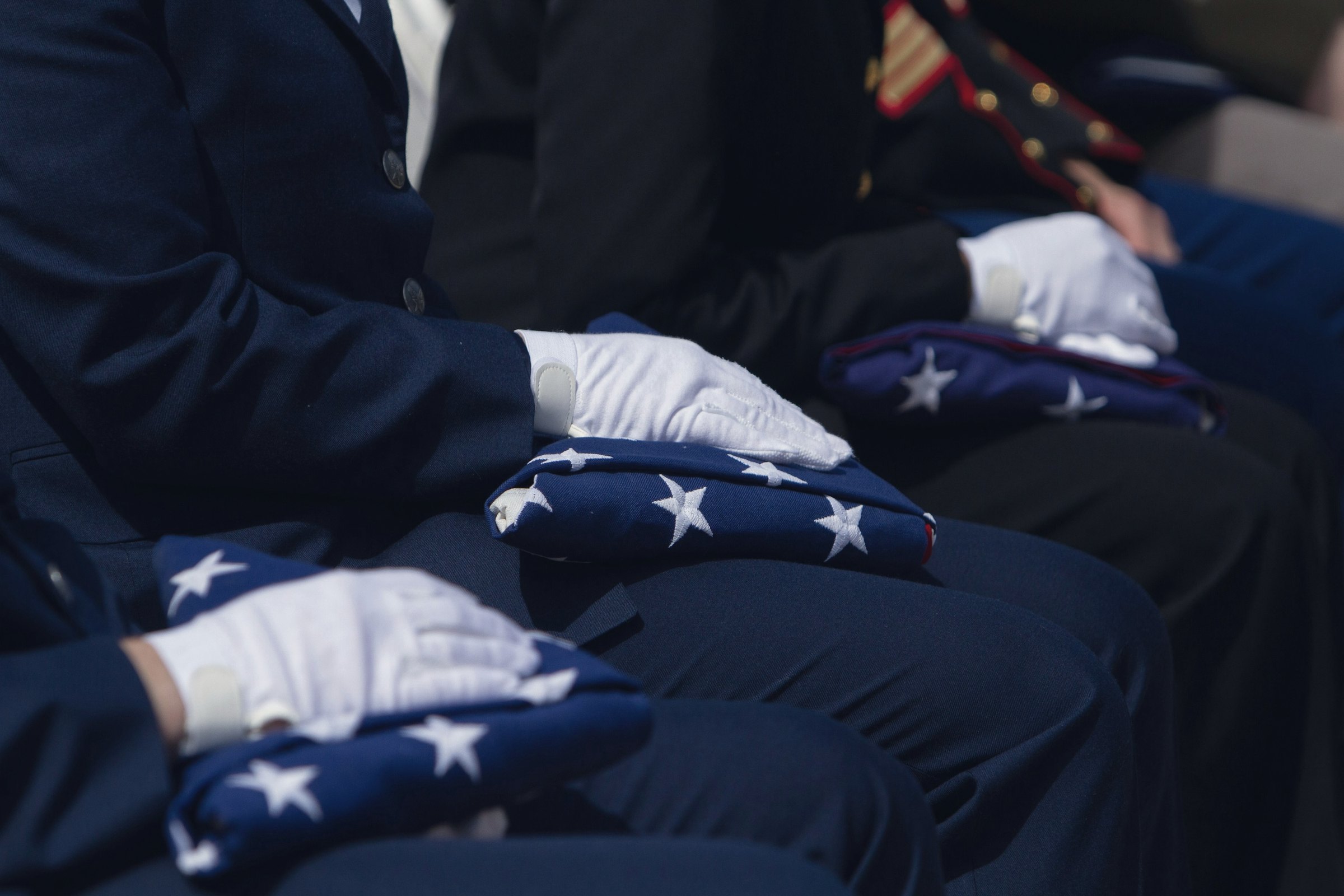 White-gloved hands resting on folded flags